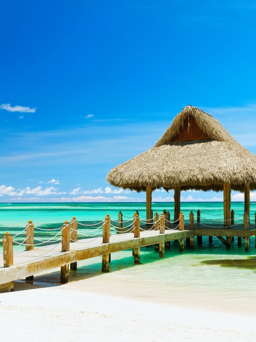 Thatched-roof pier over turquoise tropical water